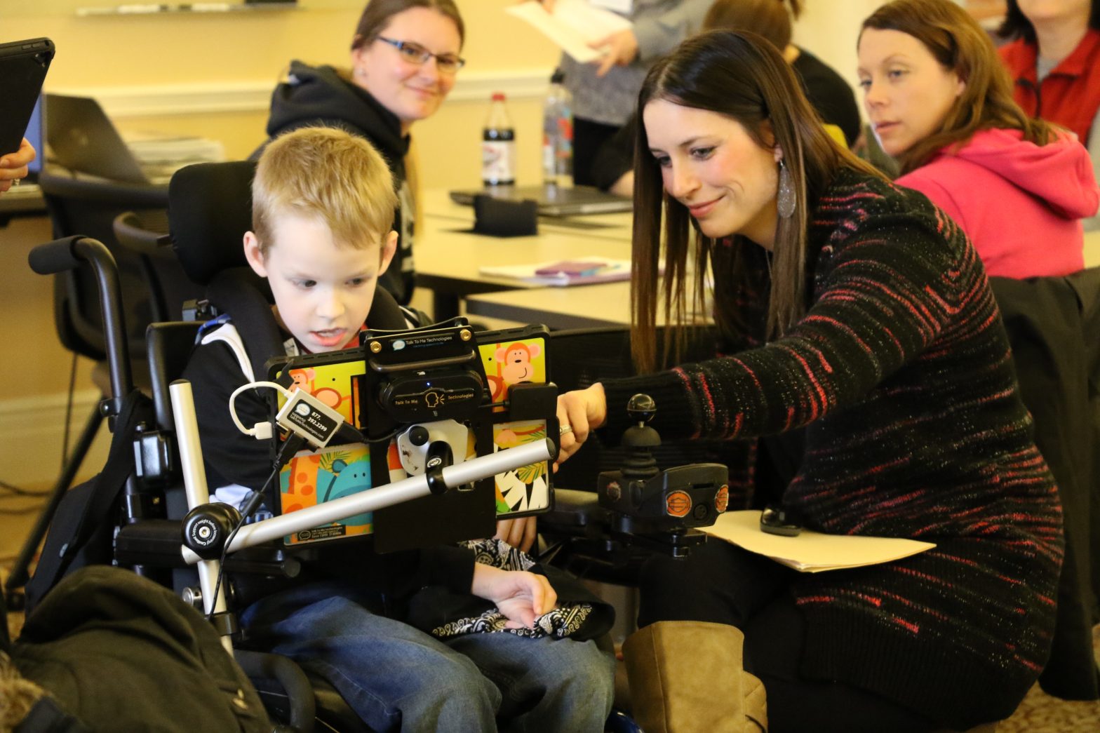 Young female staff member helping a student in a wheelchair.