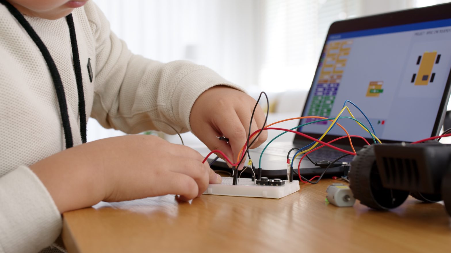 Young student remotely learn online at home in coding robot car and electronic board cable in STEM, STEAM, mathematics engineering science technology computer code in robotics for kids concept.