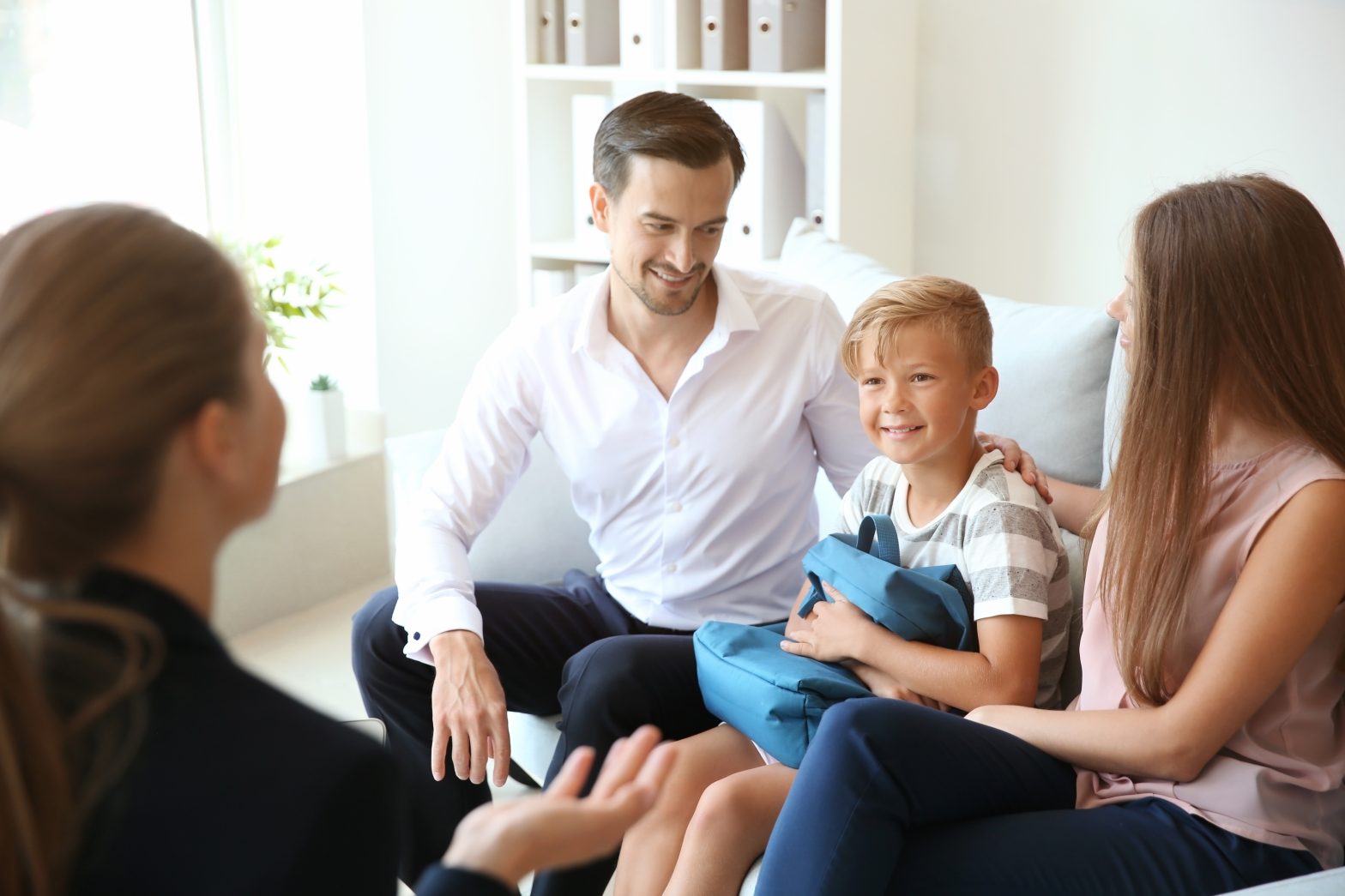 Young couple and their son meeting with headmistress at school.