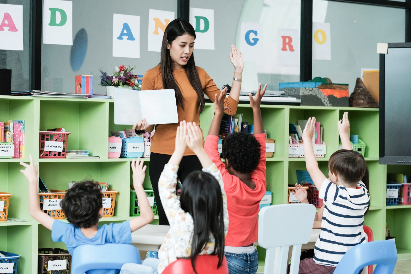 Young asian woman teacher teaching kids in kindergarten classroom