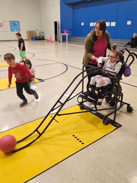 McKenna bowling with classmates using an adapted ramp for full participation in PE.