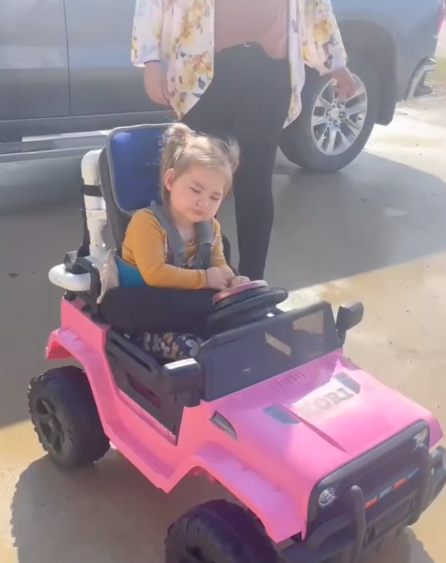 Kori riding her motorized car.